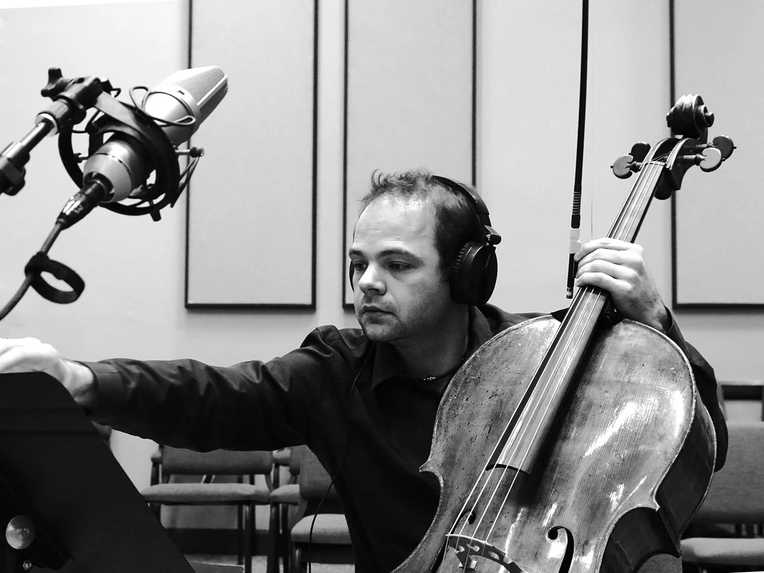 László Mező wearing headphones while recording cello beside a studio microphone